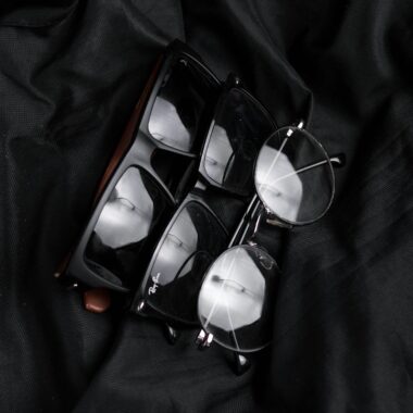 Close-up of various stylish eyeglasses on black fabric, highlighting modern eyewear design.