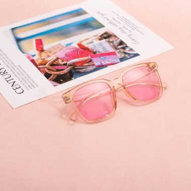 Pink sunglasses on a magazine page with a soft pastel background, capturing a chic and modern vibe.