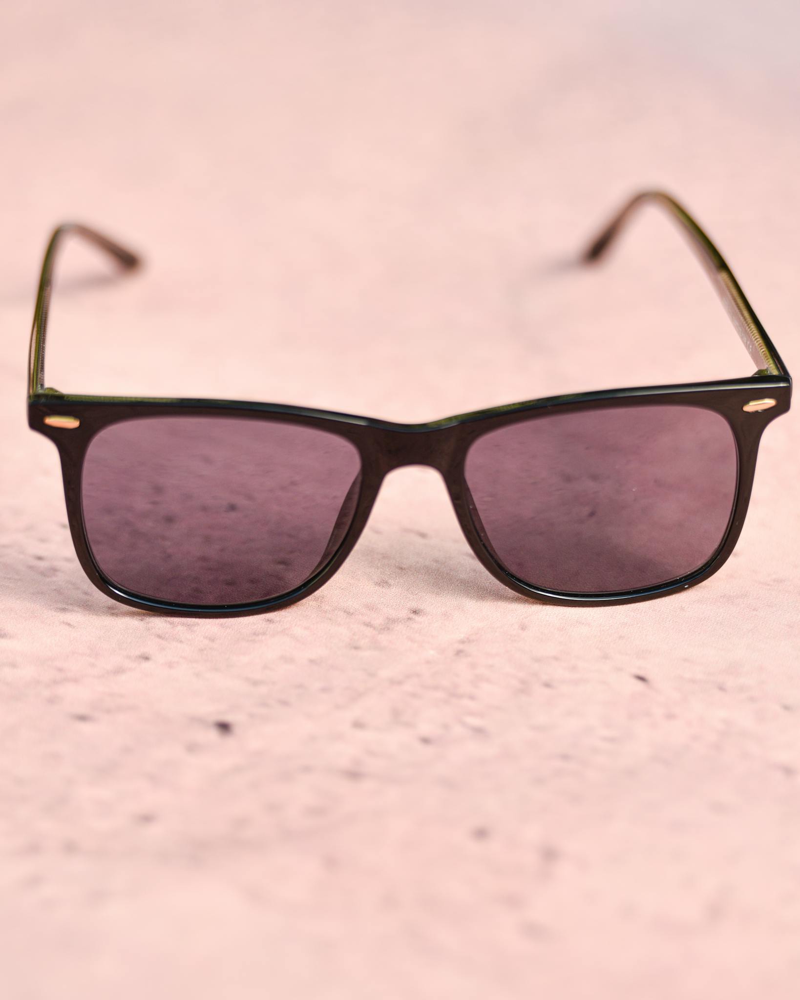Trendy pink sunglasses displayed on a light pink textured surface for a fashionable look.